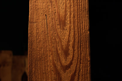 Macro perspective of sweeping vertical grain lines curving into a distinct loop pattern on a museum-quality wood surface. 