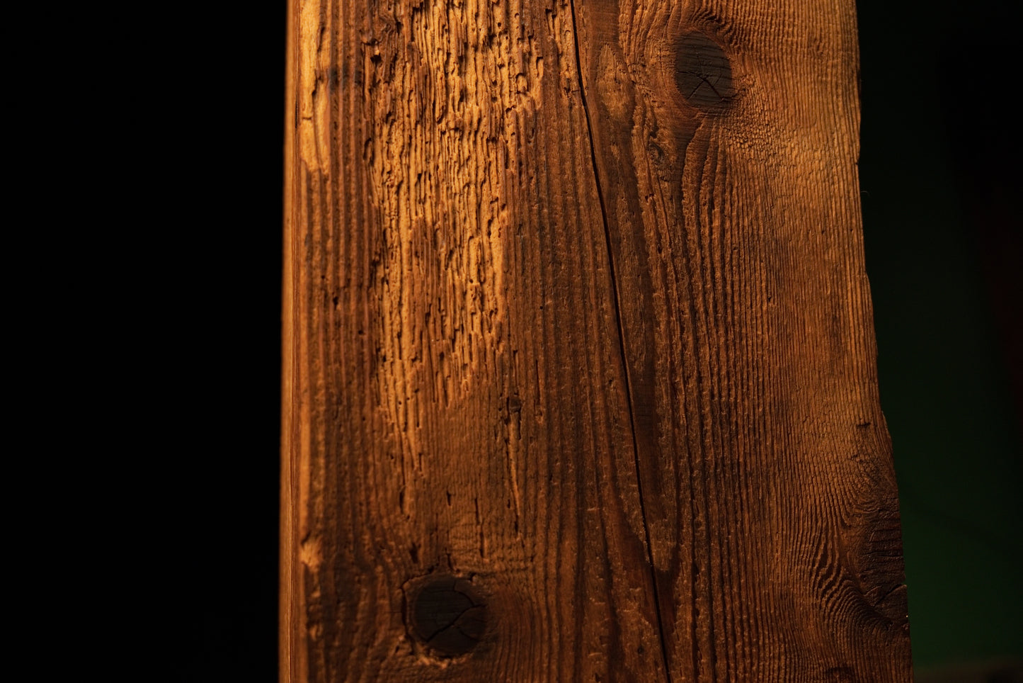 Detailed view of a small dark organic knot positioned near the lower section of a fully stabilized structural timber beam. 