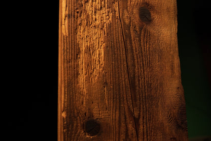 Detailed view of a small dark organic knot positioned near the lower section of a fully stabilized structural timber beam. 