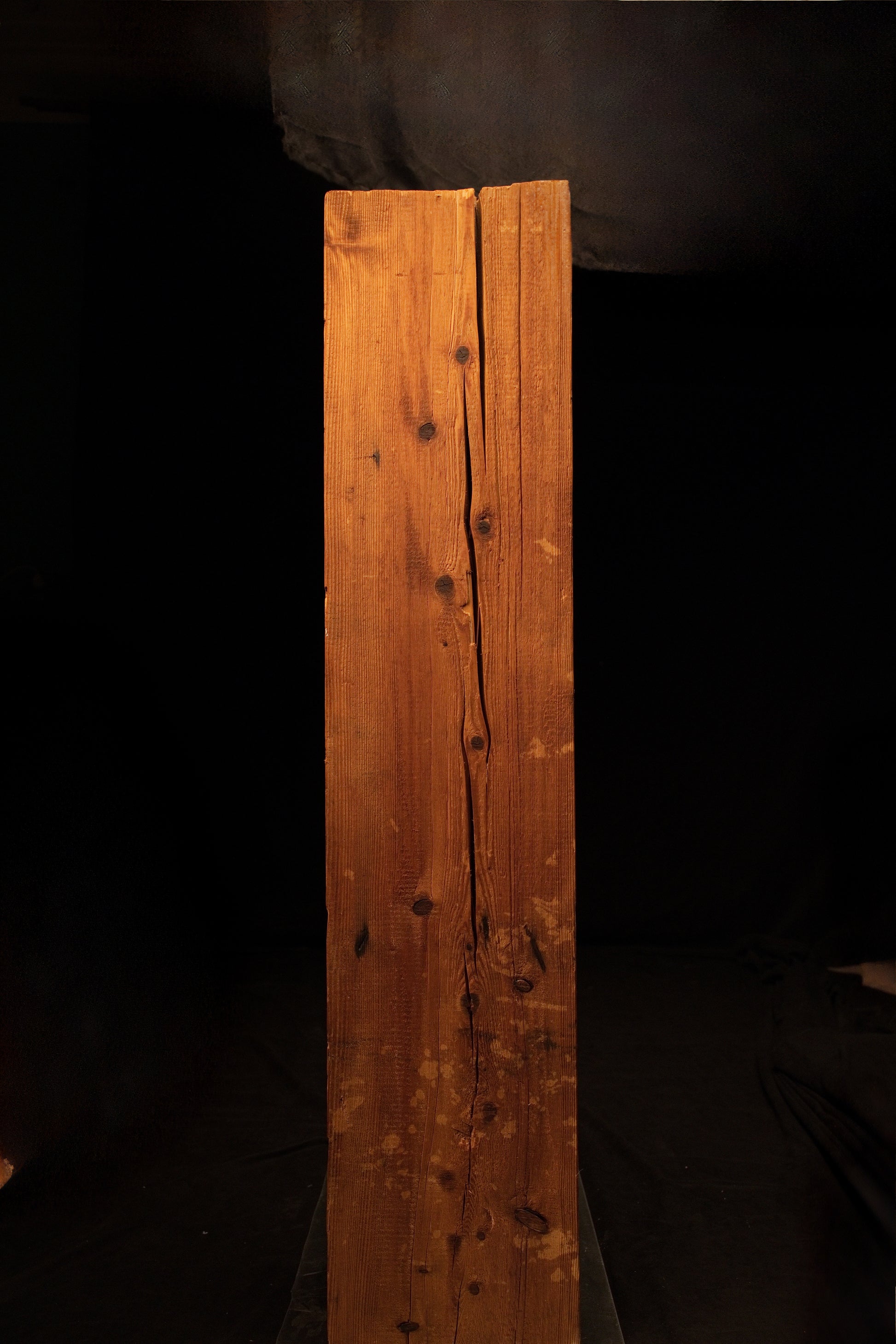 Vertical view of a floor-heating compatible timber element showcasing a prominent central split and multiple dark wood knots. 