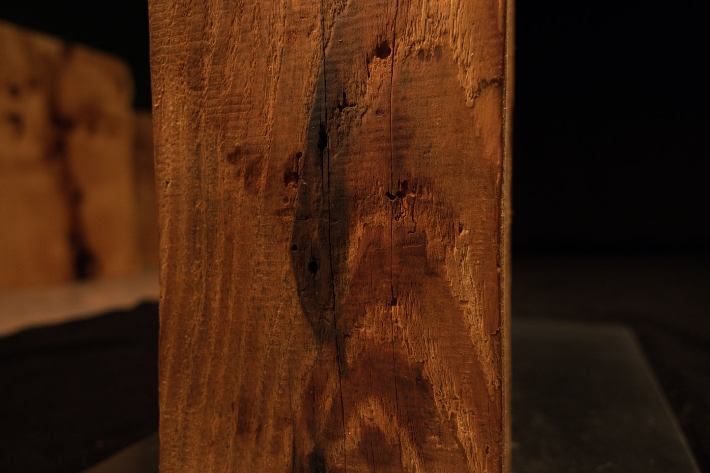 Close-up focus on a dark pocket inclusion and textured grain patterns on the vertical face of a climate-stable timber block. 