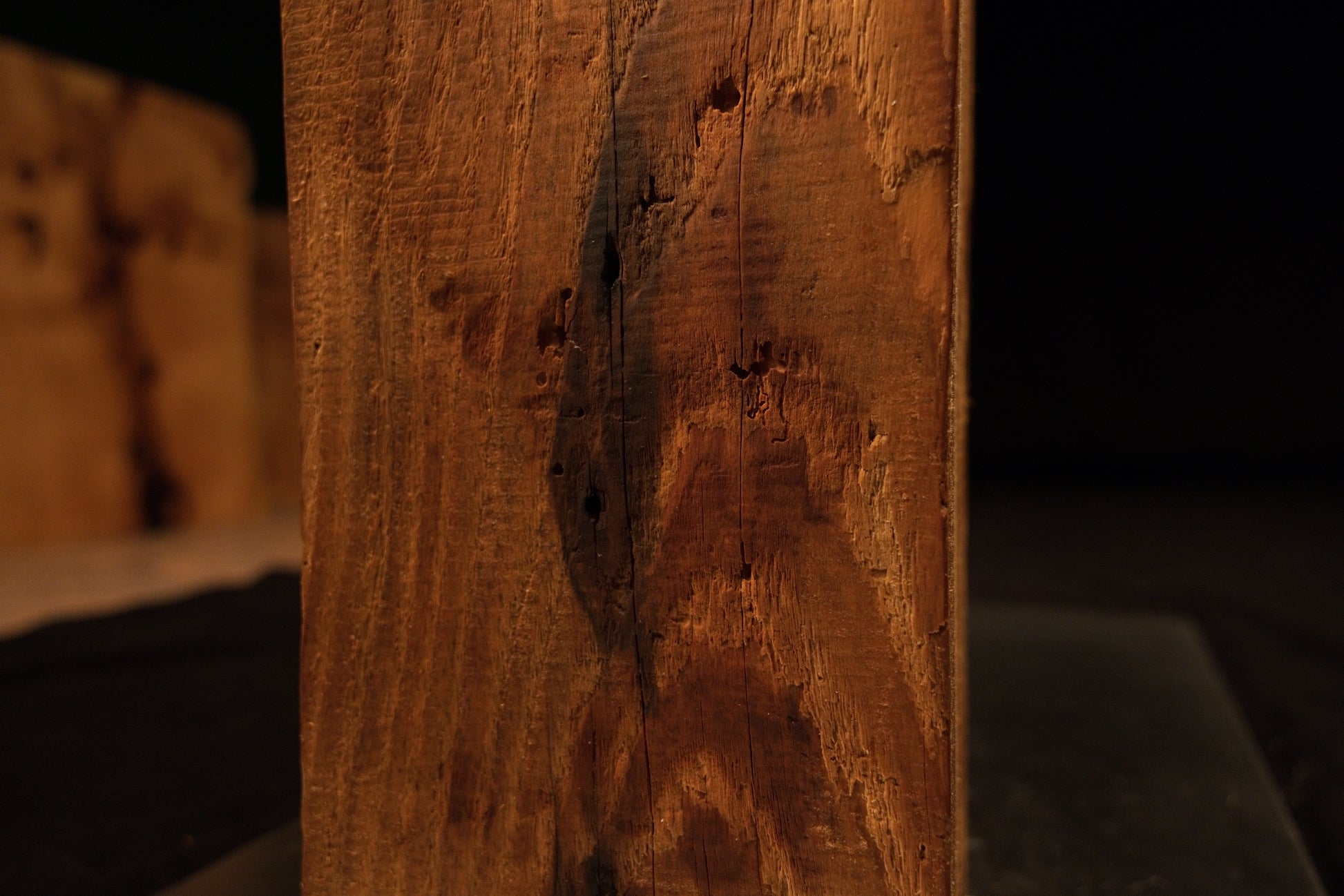 Close-up focus on a dark pocket inclusion and textured grain patterns on the vertical face of a climate-stable timber block. 