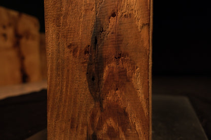 Close-up focus on a dark pocket inclusion and textured grain patterns on the vertical face of a climate-stable timber block. 
