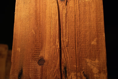 Macro view capturing a dark circular wood knot and surrounding vertical golden fibers on an interior architectural block face. 