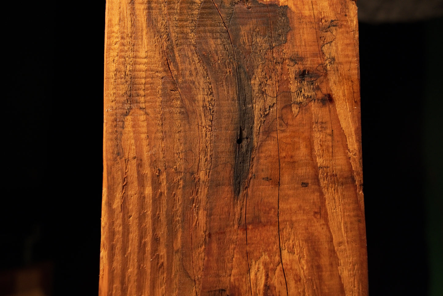 Close perspective of a dark oxidized zone and surface checking near the upper portion of a floor-heating safe wood beam. 