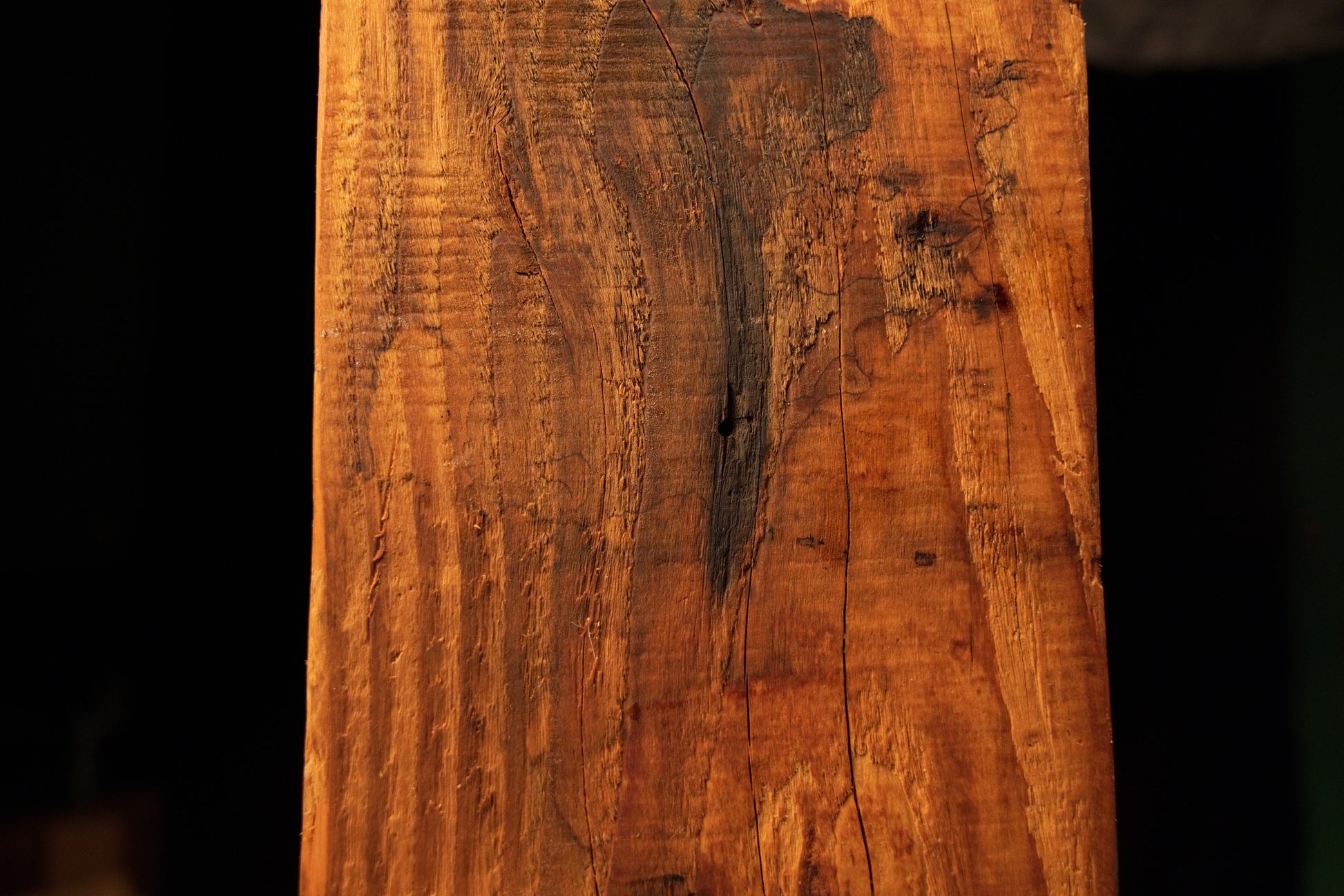 Close perspective of a dark oxidized zone and surface checking near the upper portion of a floor-heating safe wood beam. 