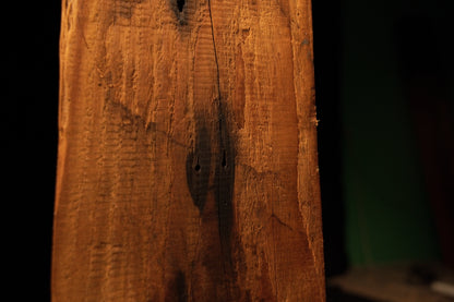 Extreme close-up of a dark organic inclusion nestled within deeply furrowed vertical wood grain on a commercial timber piece. 