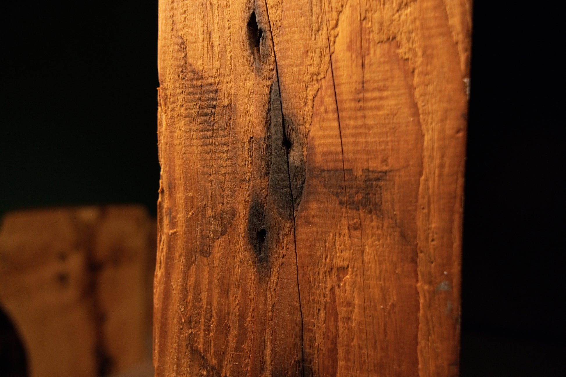 Close-up of a narrow central groove and dark organic knot cavities on the textured vertical face of a climate-stable timber. 