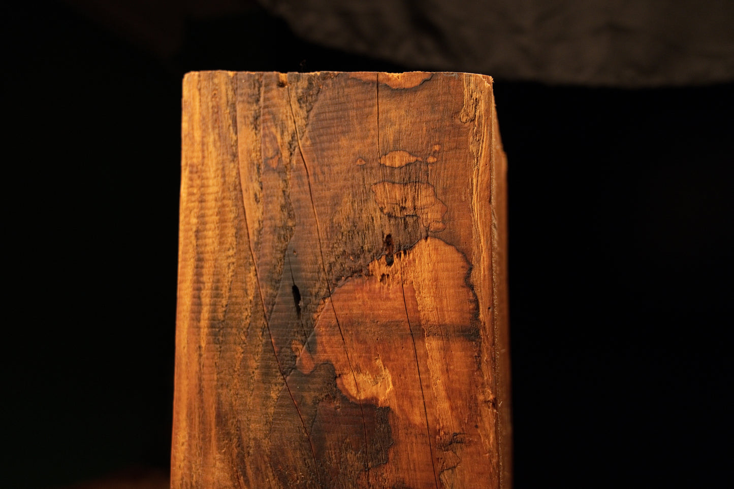 Detailed close-up of a mottled dark surface discoloration pattern spreading across the vertical face of a structural timber slab. 