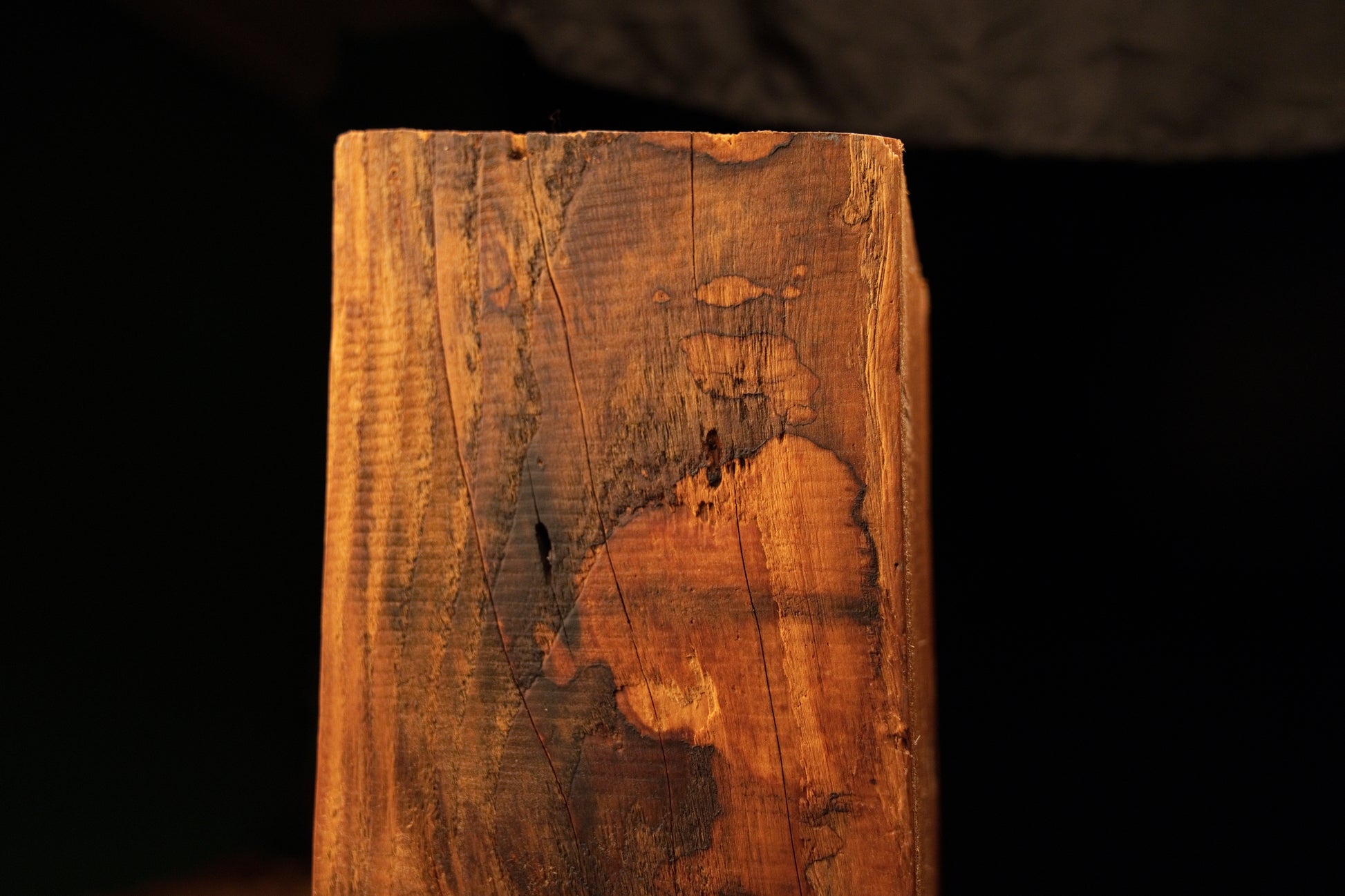 Detailed close-up of a mottled dark surface discoloration pattern spreading across the vertical face of a structural timber slab. 