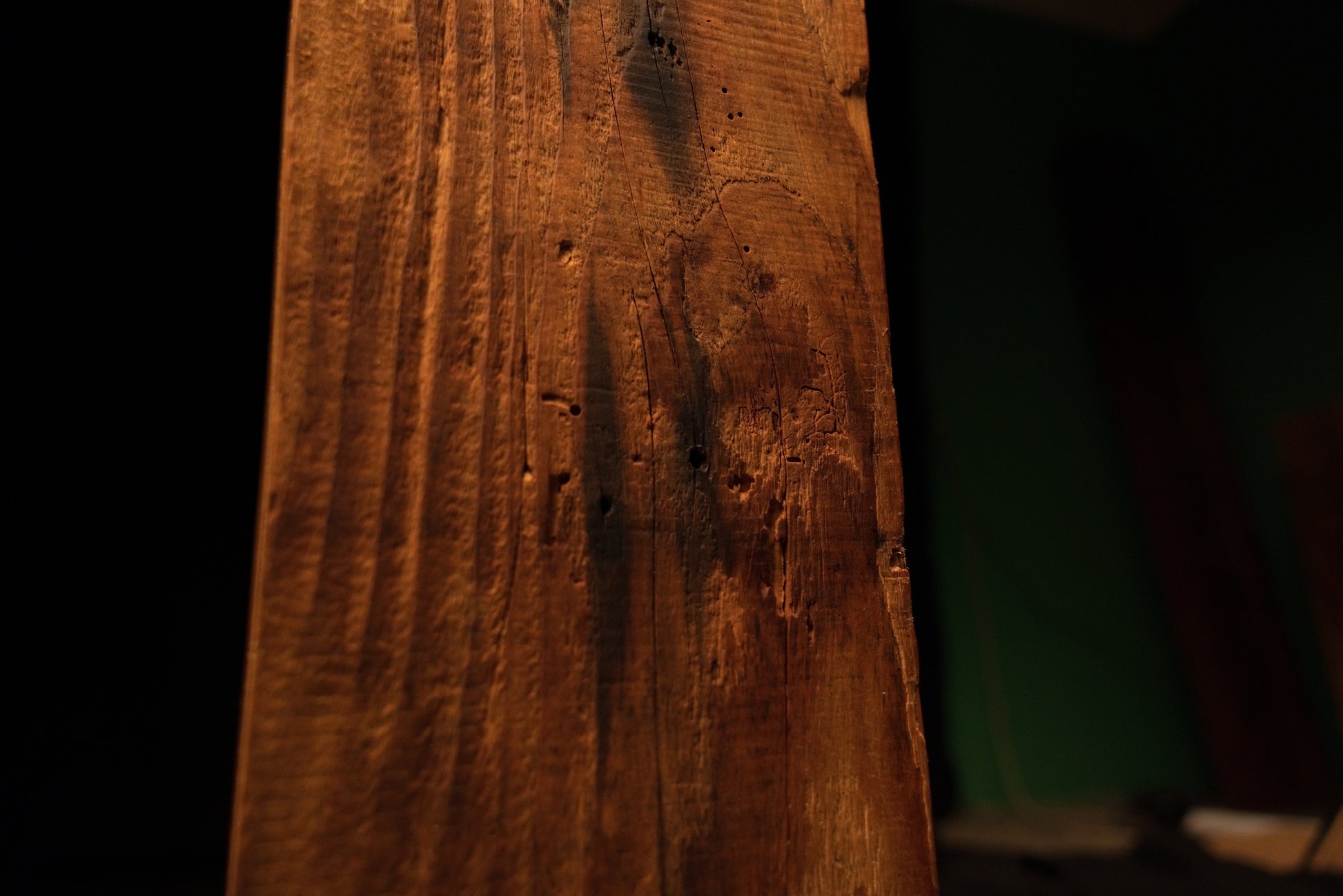 Detailed macro close-up of shallow surface pitting and vertical grain lines running along the face of a structural timber block. 