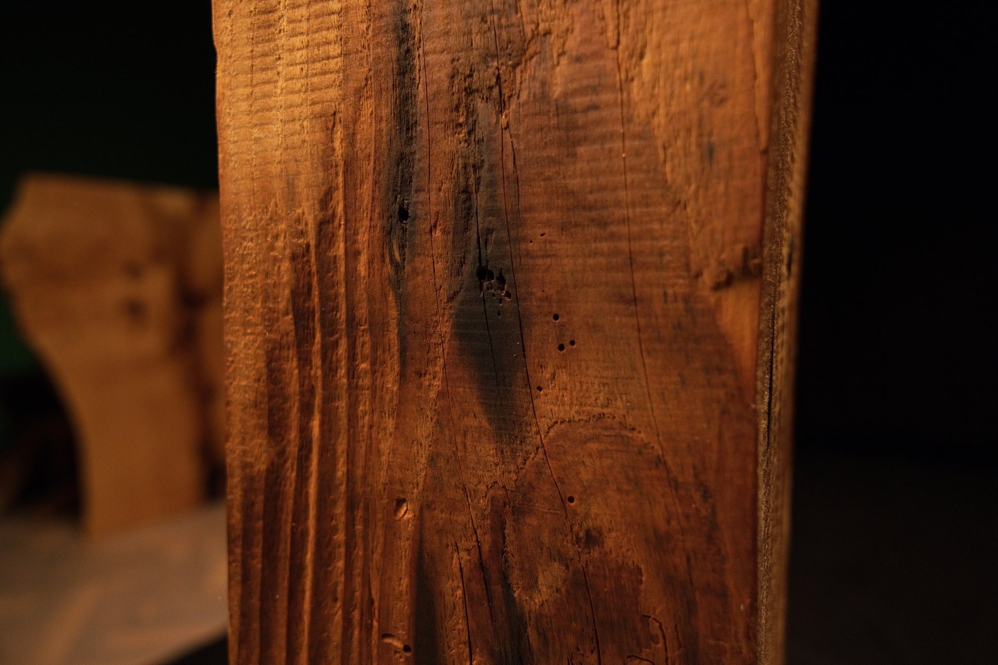Macro photograph showing dark biological spots and small micro-cracks distributed evenly across the vertical grain of a wooden beam. 