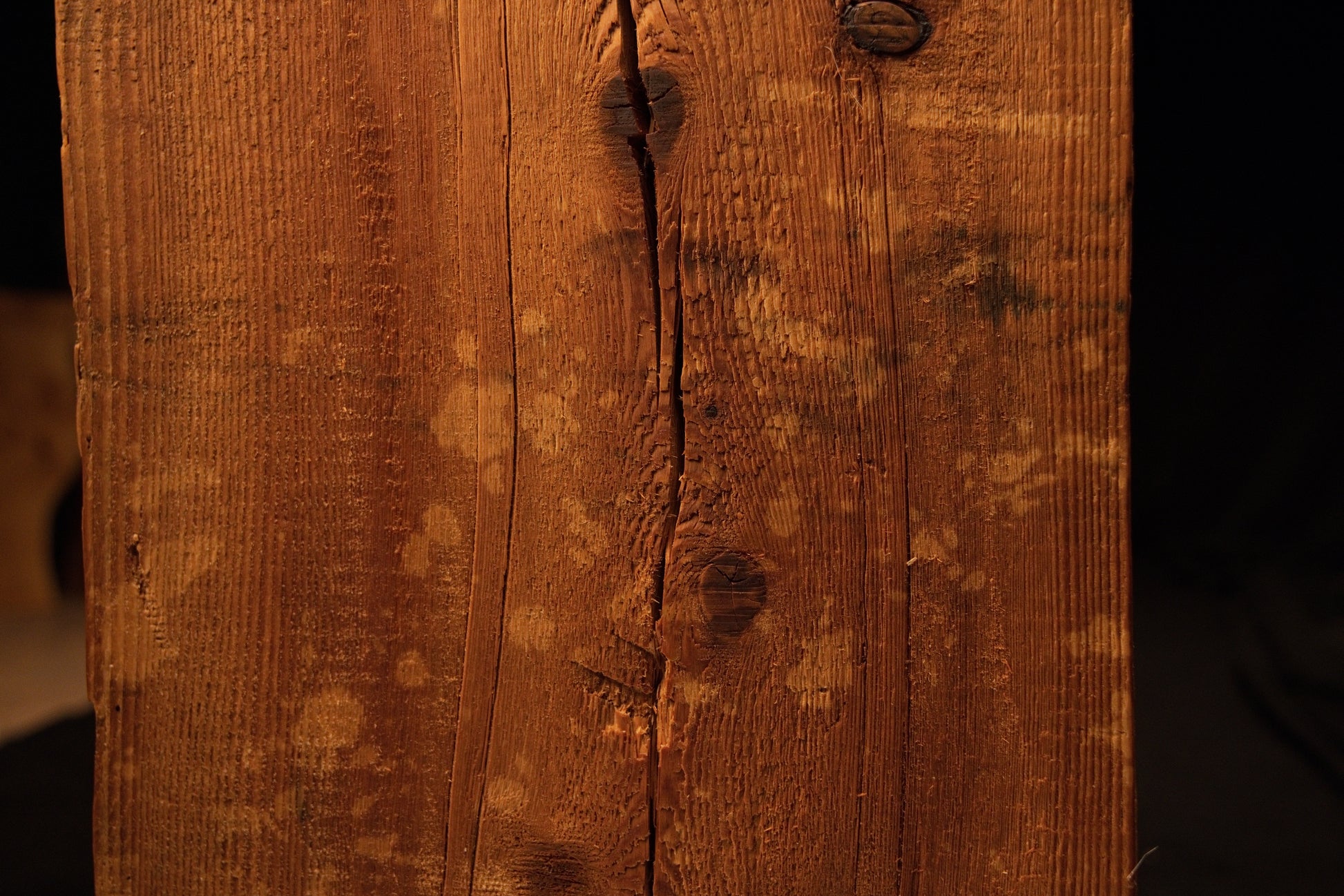 Detailed close-up view of the wooden beam surface featuring lighter circular stain spots spreading around a central vertical split. 