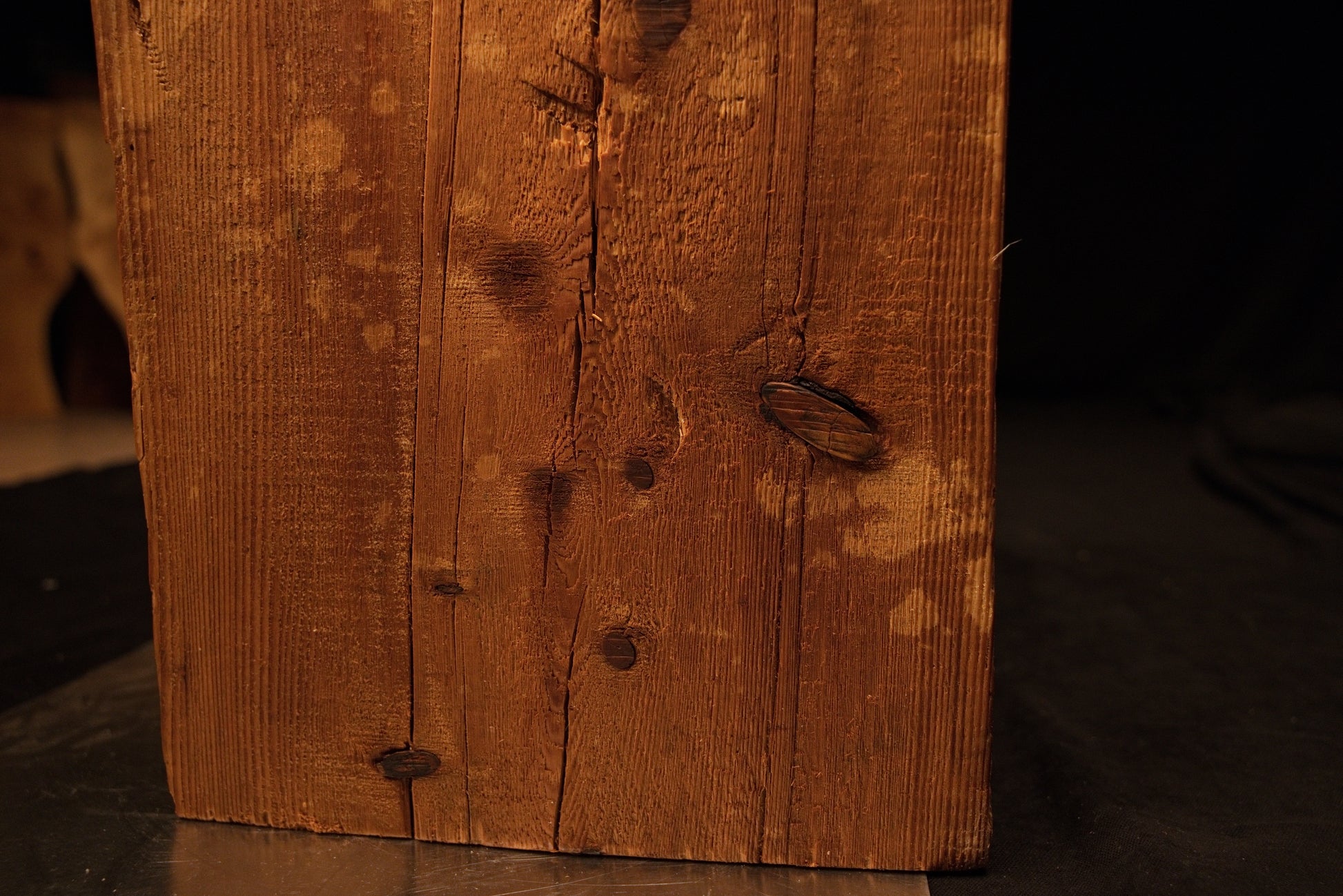 Detailed close perspective of the lower beam section showing a dark rectangular wooden patch inserted tightly near the right edge. 
