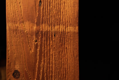 Macro photograph of the lower timber section resting directly on the metal base plate with visible vertical grain textures. 