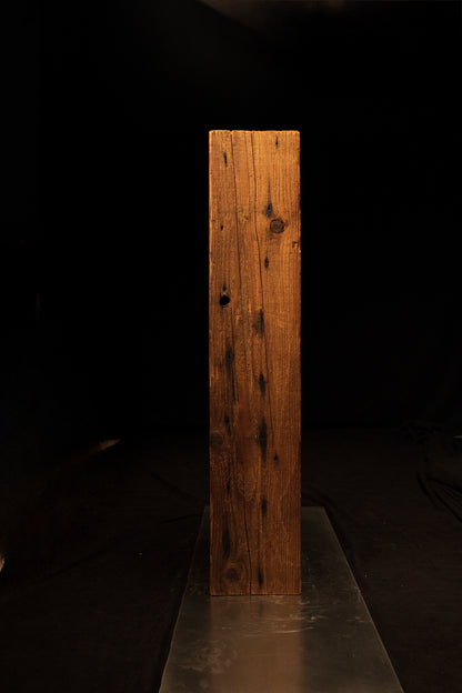 Vertical profile view of a structural wooden beam displaying tight linear grain lines and small dark knot formations. 