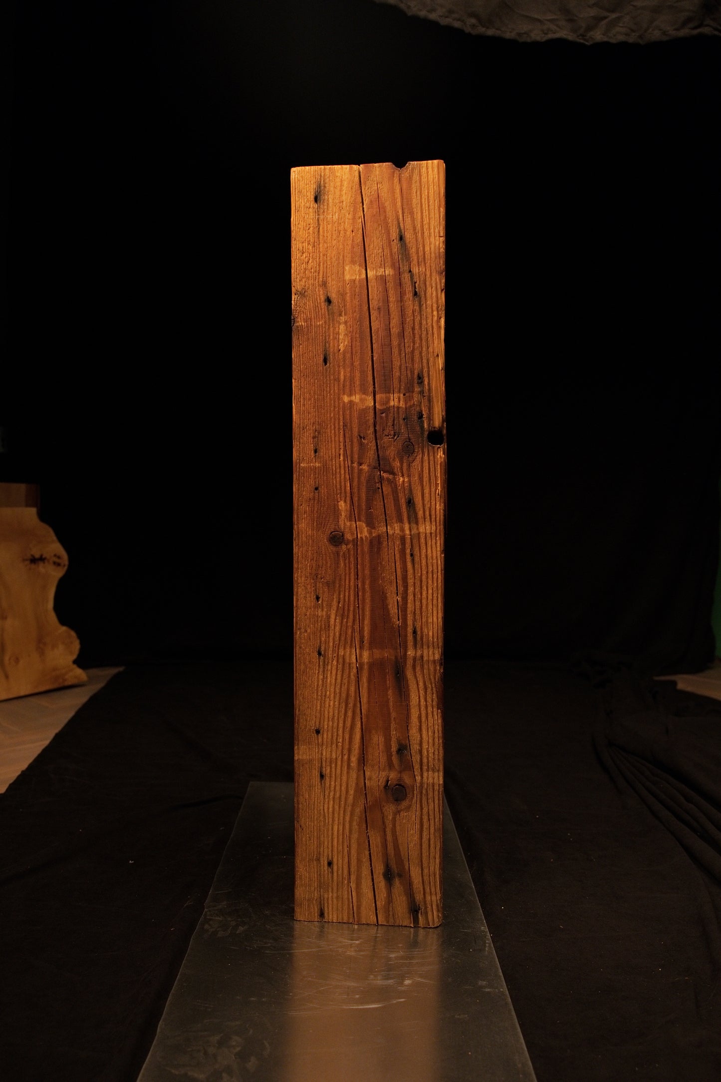 Full length view of a rectangular wooden post highlighting fine horizontal saw marks intersecting the vertical grain. 