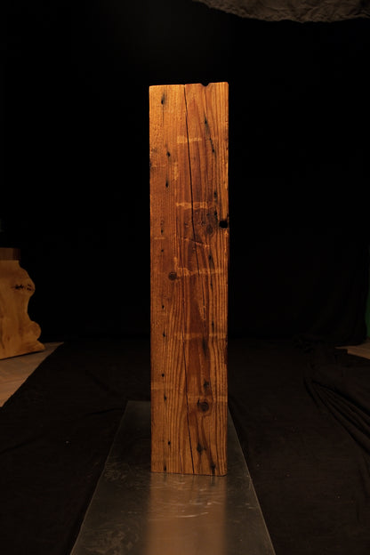 Full length view of a rectangular wooden post highlighting fine horizontal saw marks intersecting the vertical grain. 