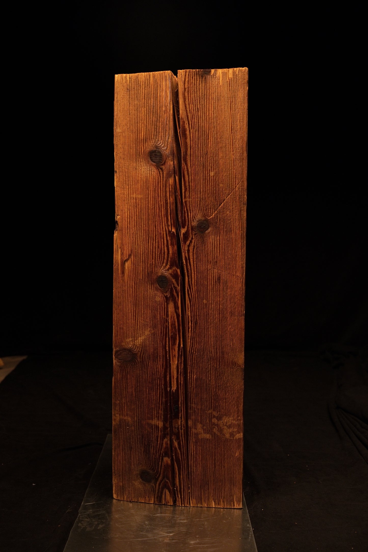 Frontal perspective of a tall timber beam featuring a prominent central vertical split flanked by dark rounded knots. 
