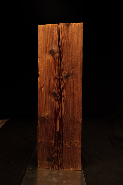 Frontal perspective of a tall timber beam featuring a prominent central vertical split flanked by dark rounded knots. 