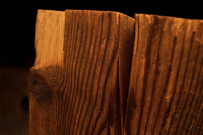 Close-up macro view of the top edge on a timber beam showing a widening vertical split dividing the textured grain. 