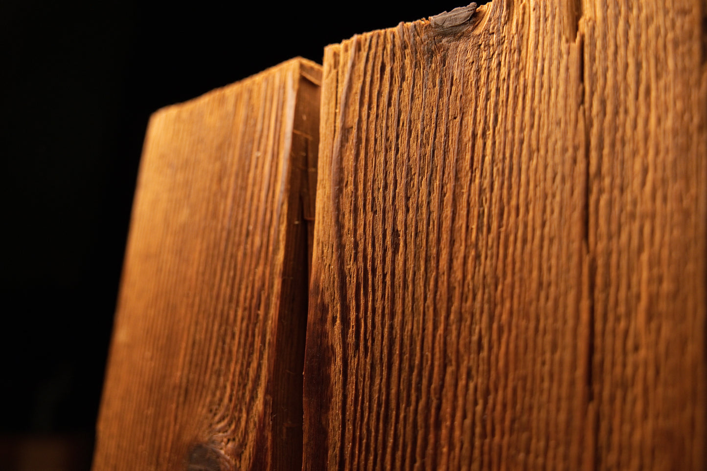 Close-up perspective of the upper corner on a vertical wooden beam highlighting textured grain and a corner split. 