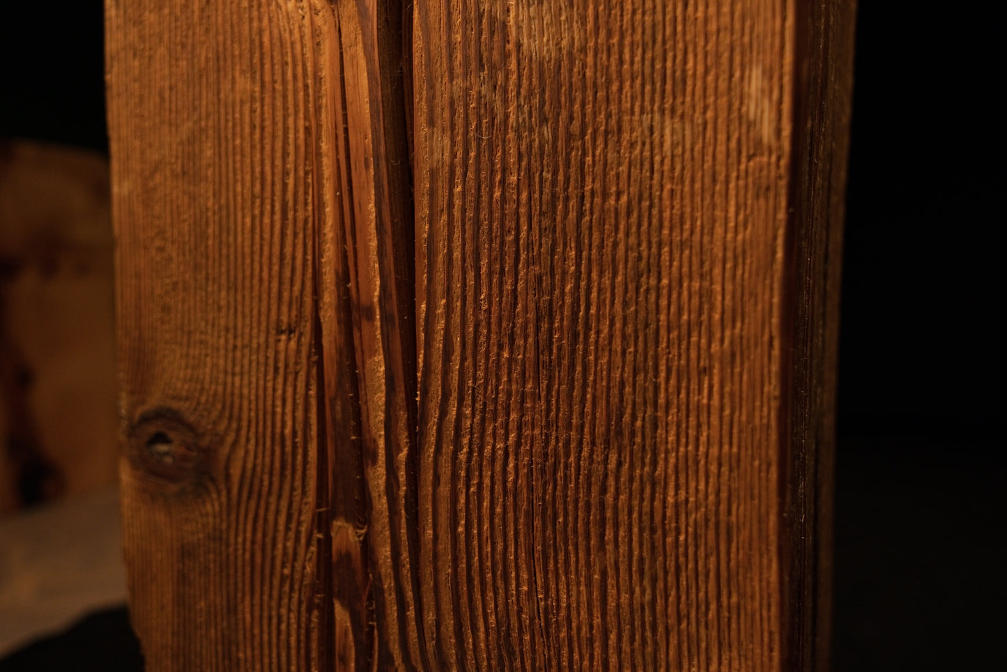 Close-up view of vertical wood grain curving around a dark embedded knot near the lower edge of the beam. 