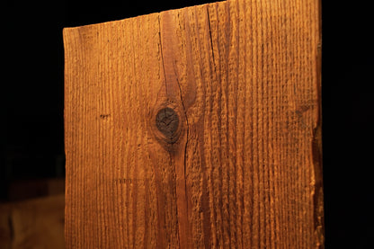 Detailed frontal view of the upper timber section centered on a prominent dark circular knot surrounded by straight grain. 