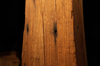 Detailed view of the beam face showing dark circular stain spots and pinholes scattered along a vertical fracture. 