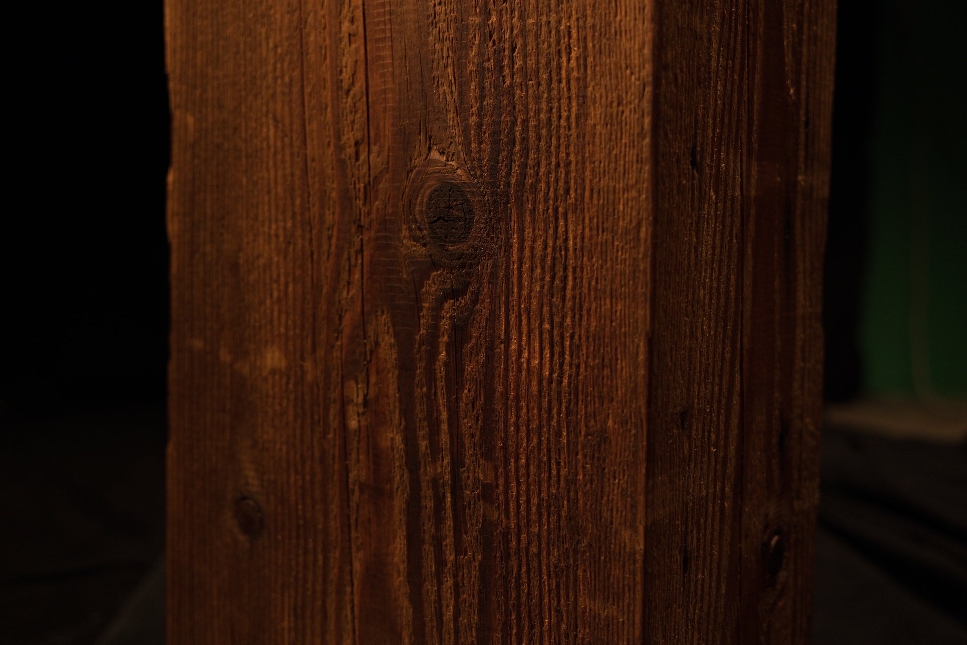 Macro photograph highlighting swirling wood grain patterns converging around a dark circular knot on the beam. 