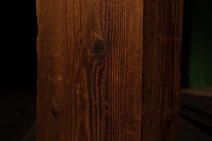 Macro photograph highlighting swirling wood grain patterns converging around a dark circular knot on the beam. 