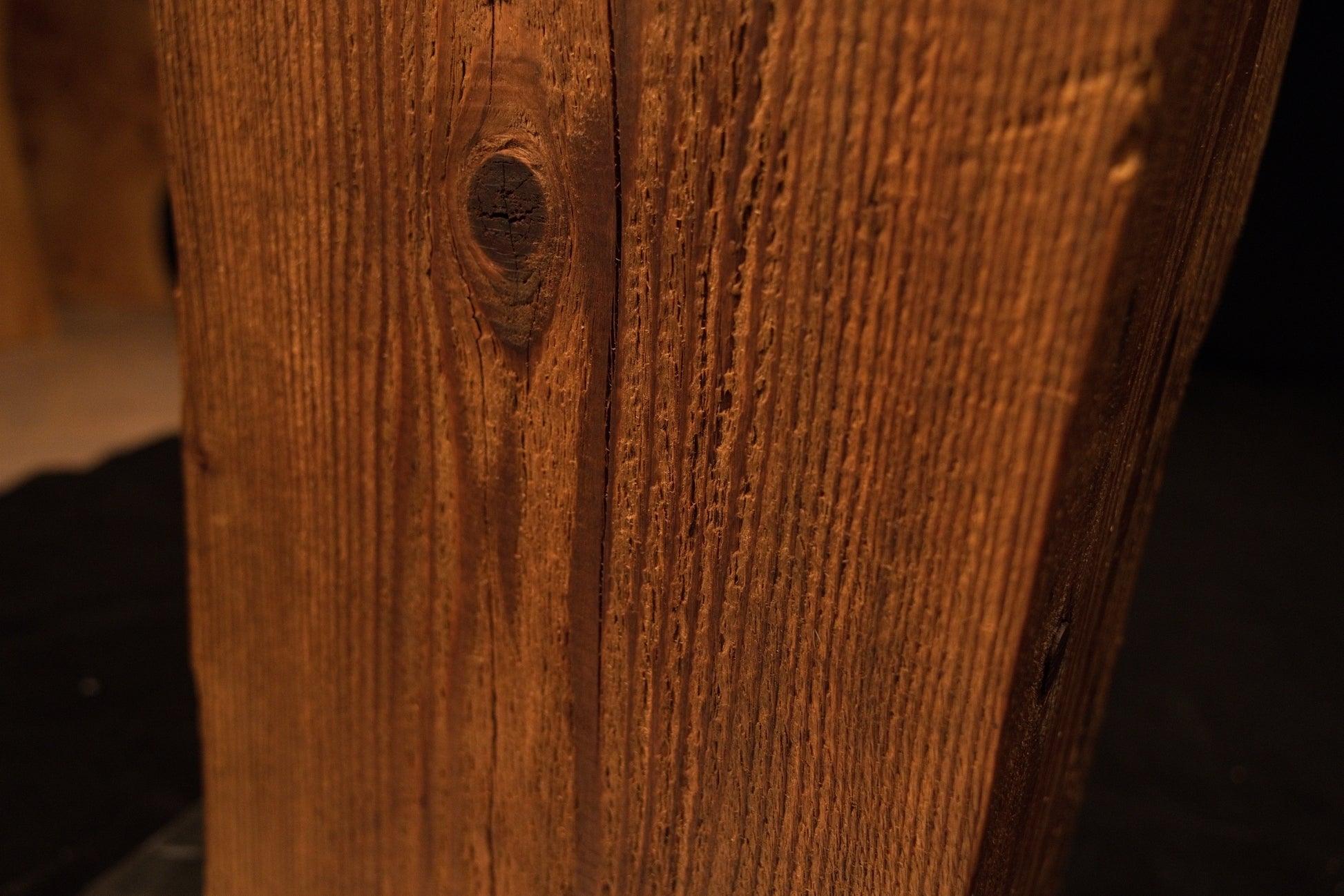 Macro view focusing on tight vertical grain lines and a small dark circular knot on the side of the wooden column. 