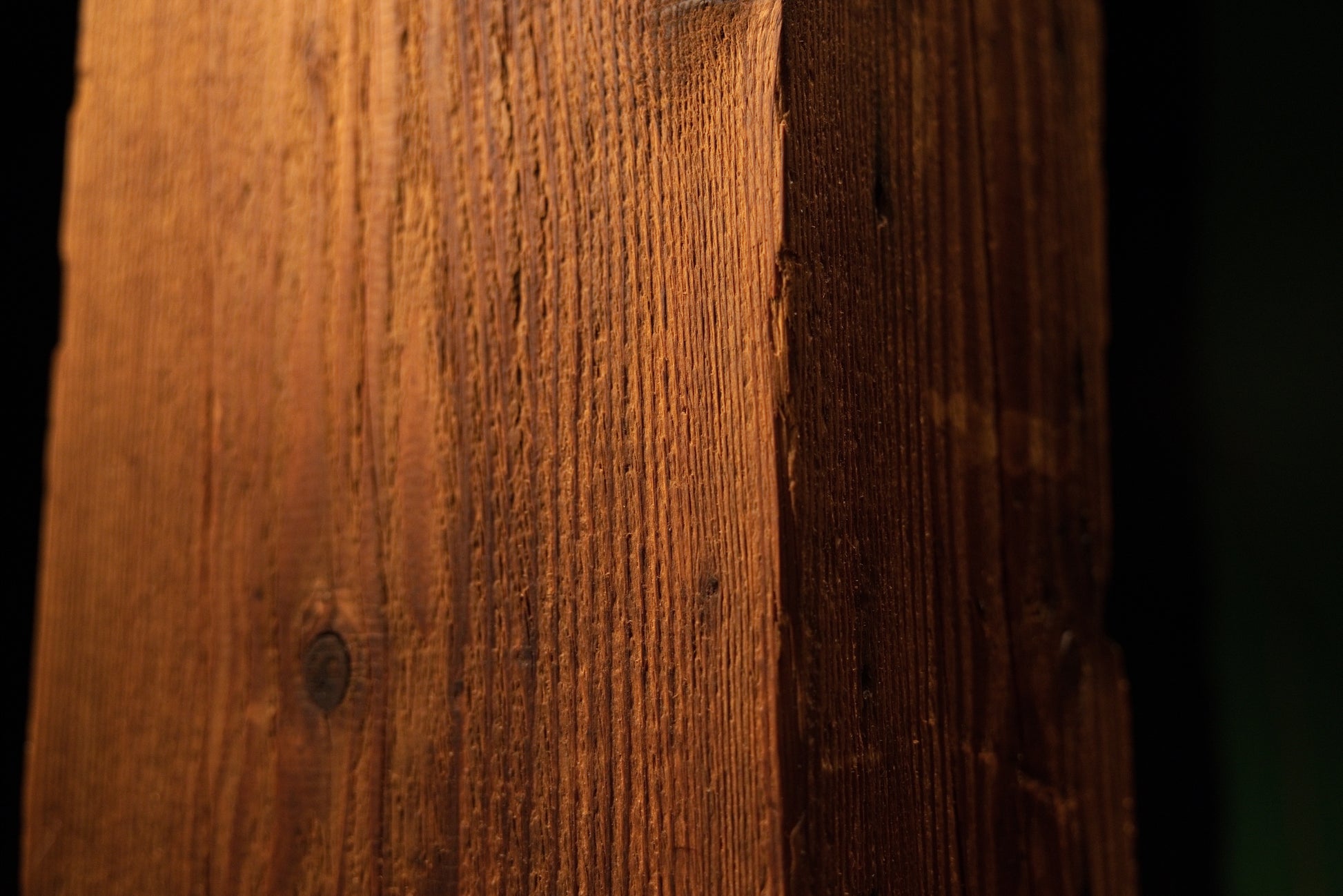 Perspective macro view capturing the vertical corner edge and linear grain patterns of the structural timber post. 