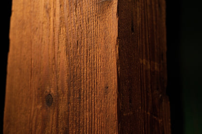 Perspective macro view capturing the vertical corner edge and linear grain patterns of the structural timber post. 