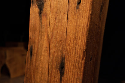 Detailed view highlighting dark discolored spots and a fine vertical fracture line on the textured wooden column. 
