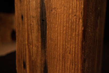 Macro photograph of straight vertical grain lines and subtle surface variations on the face of the wooden beam. 