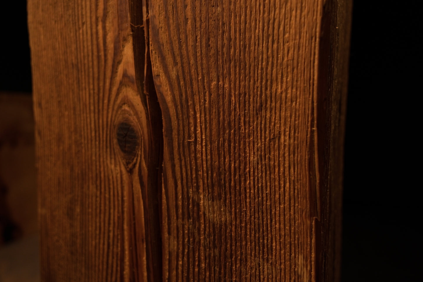 Close-up perspective showing vertical wood grain curving around a dark circular knot on the timber surface. 