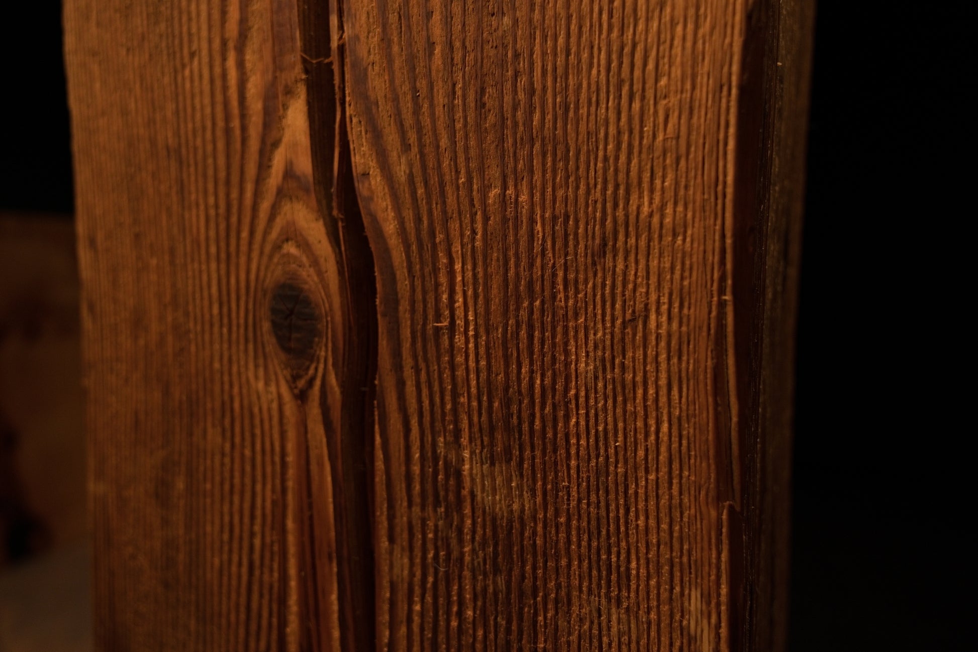 Close-up perspective showing vertical wood grain curving around a dark circular knot on the timber surface. 