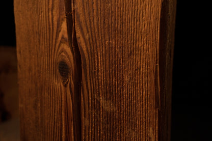 Close-up perspective showing vertical wood grain curving around a dark circular knot on the timber surface. 