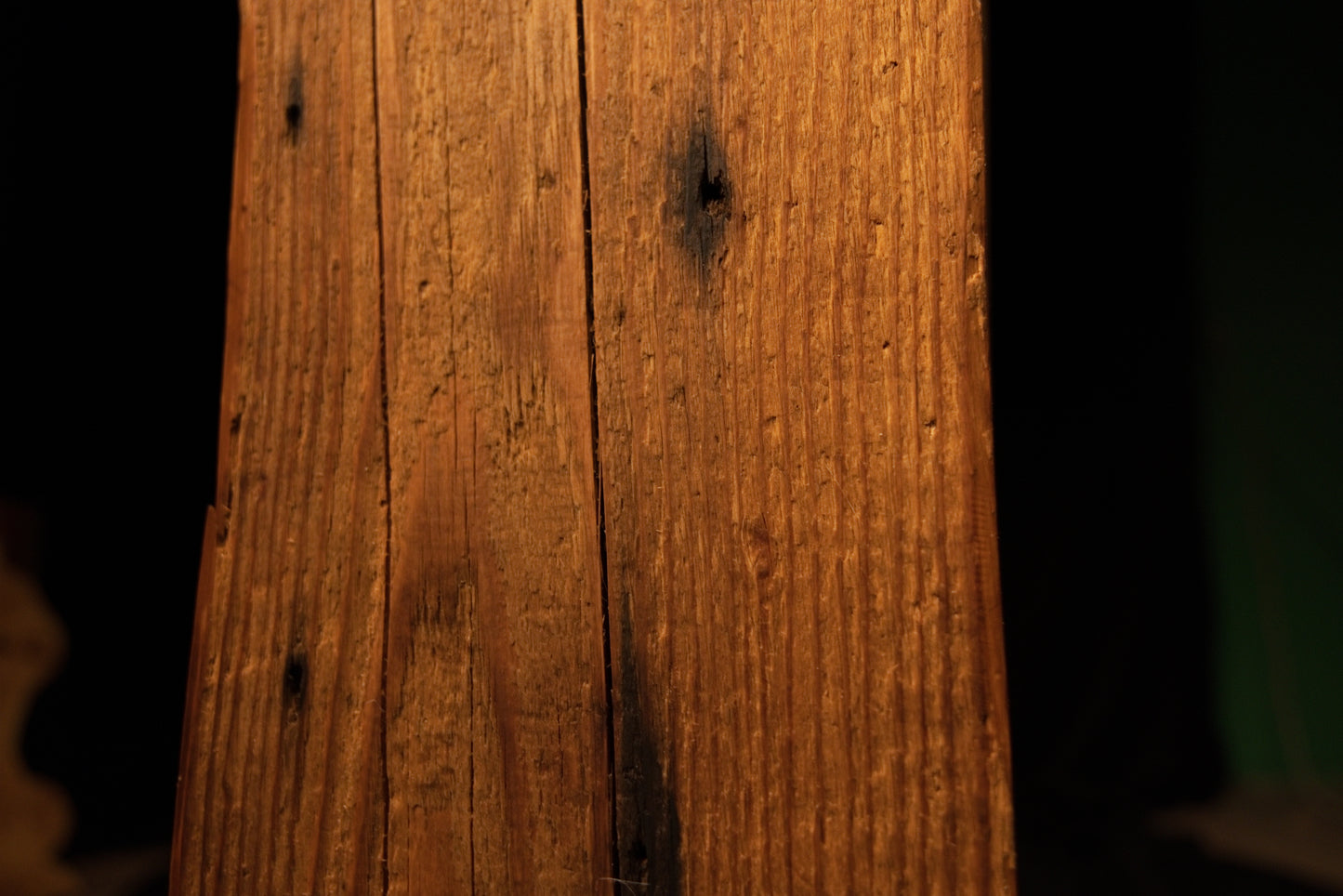 Detailed view of the weathered beam face featuring scattered pinholes, fine vertical cracks, and dark spots. 
