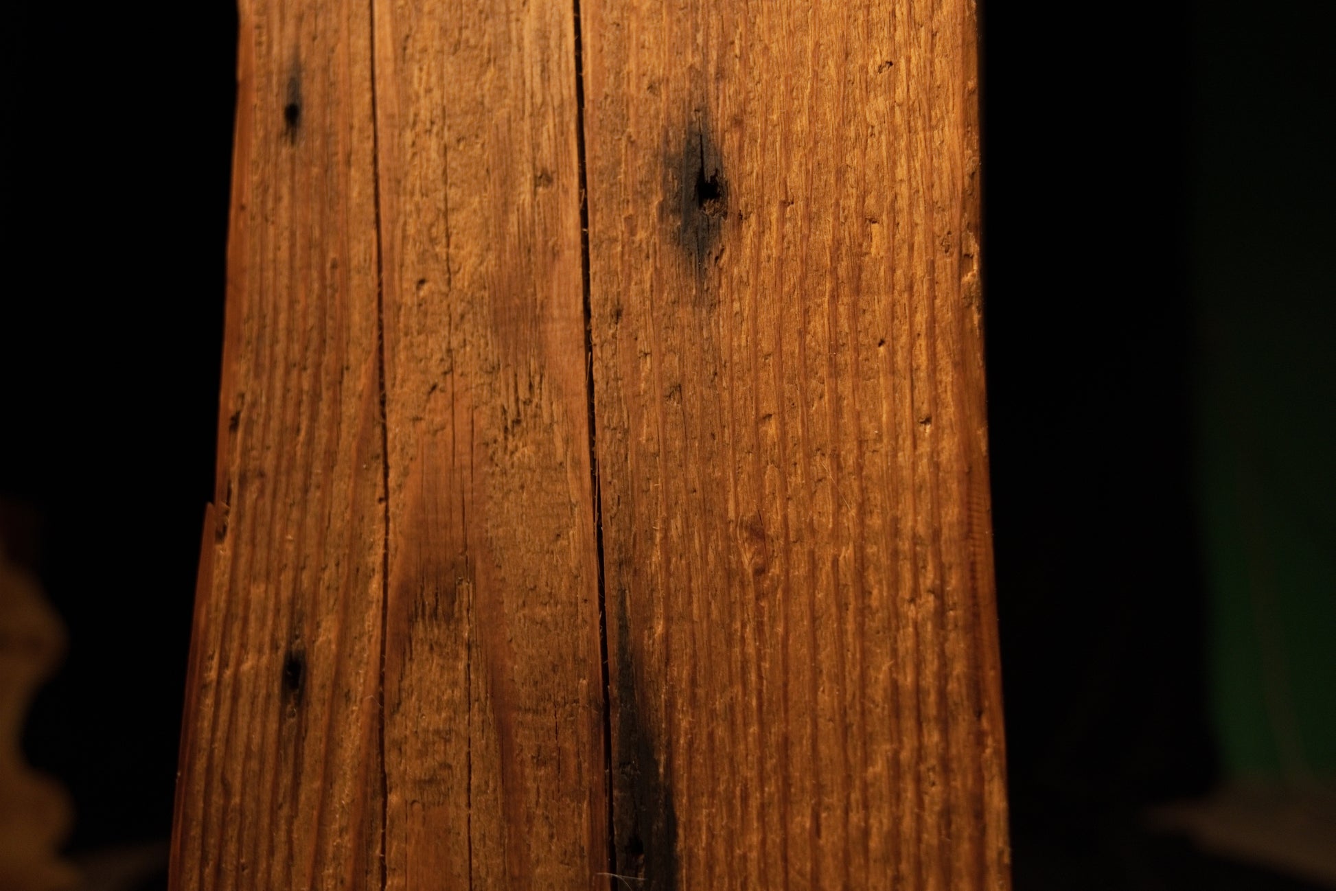 Detailed view of the weathered beam face featuring scattered pinholes, fine vertical cracks, and dark spots. 