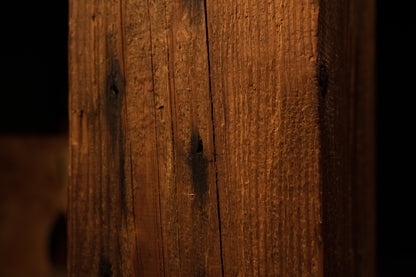 Macro photograph capturing the lower vertical corner edge and fine linear grain textures of the wooden column. 