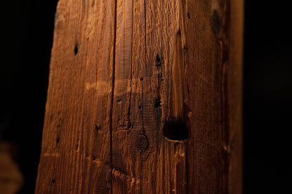 Detailed close-up showing a prominent dark circular hole, pinholes, and vertical splits on the beam surface. 