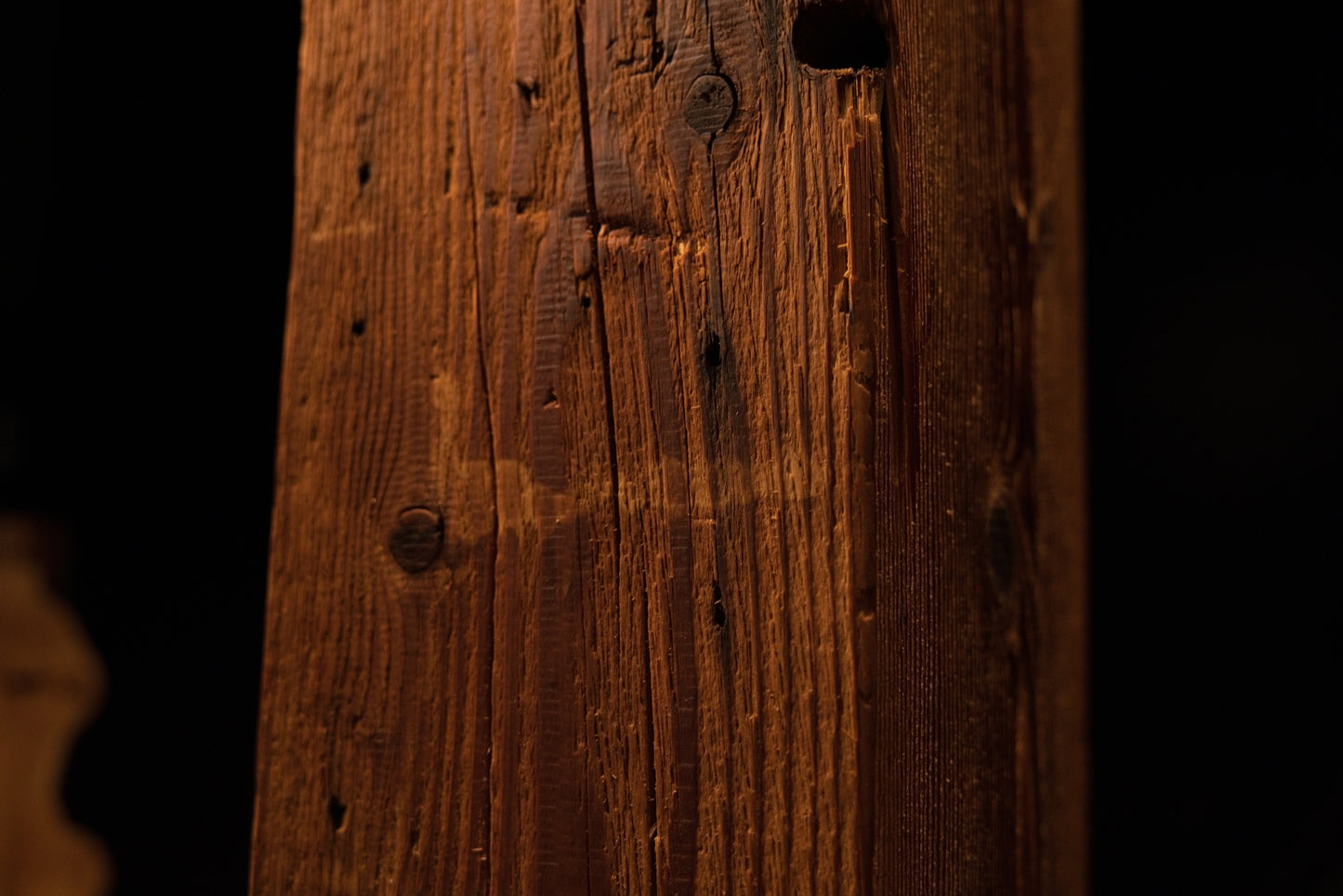 Close-up perspective capturing a dark void opening near the top edge alongside fine vertical surface fractures. 