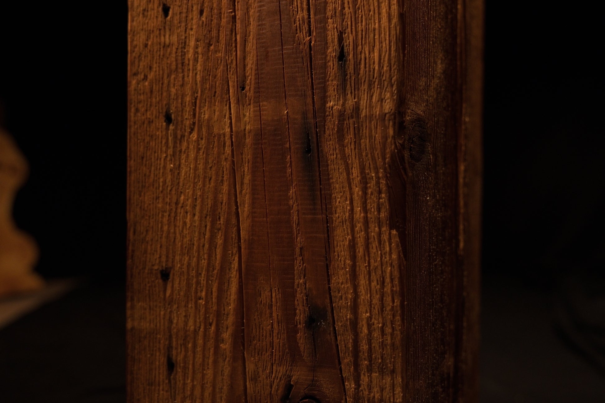 Detailed view of the lower beam section displaying weathered vertical grain textures and small dark pinholes. 