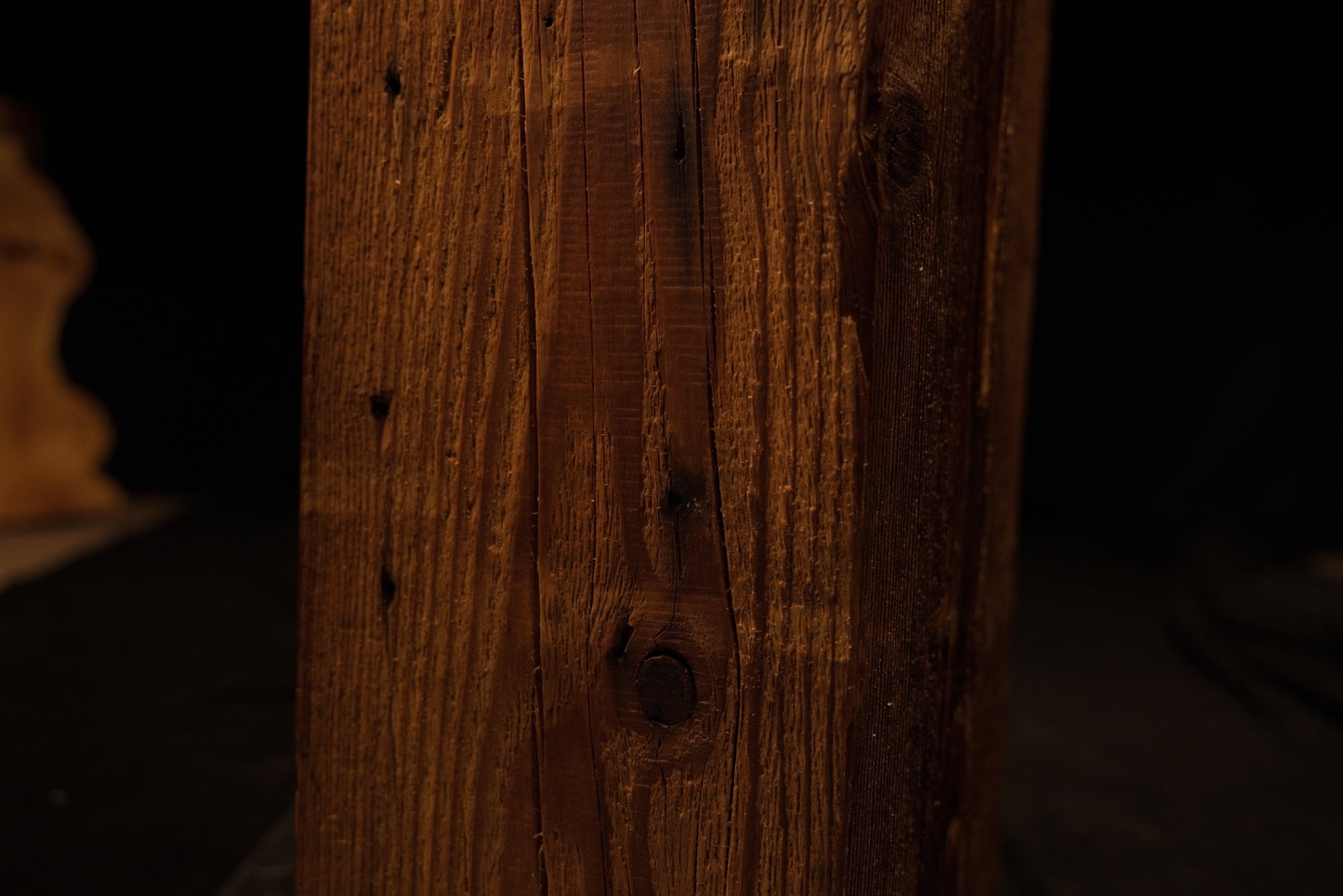 Macro photograph focusing on the lower-middle face of the wooden column with linear grain and minor blemishes. 