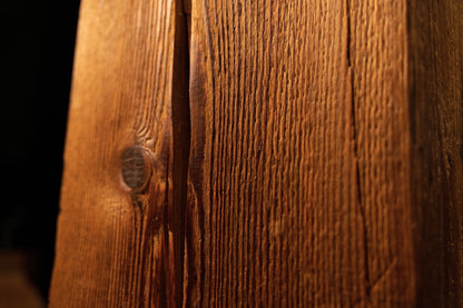 Close-up view of the bottom timber section showcasing tight vertical grain lines and dark organic inclusions. 