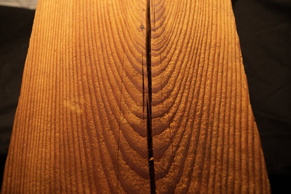 Detailed macro shot capturing swirling parabolic cathedral grain curves framing a central split in a timber piece. 