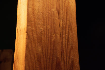 Detailed macro view of straight vertical grain running continuously along the side edge of a structural wooden beam. 