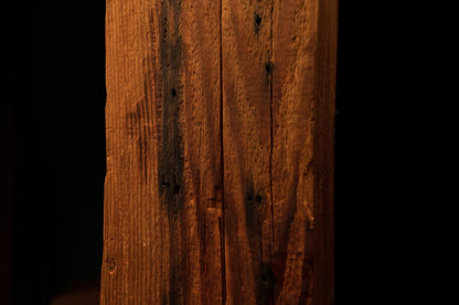 Detailed close-up of a dark oxidation stain stretching alongside a central vertical crack on a wooden beam face. 